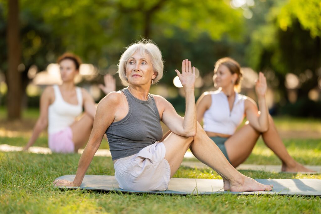 smiling,senior,silver haired,woman,enjoying,group,yoga,practice,outdoors,,sitting