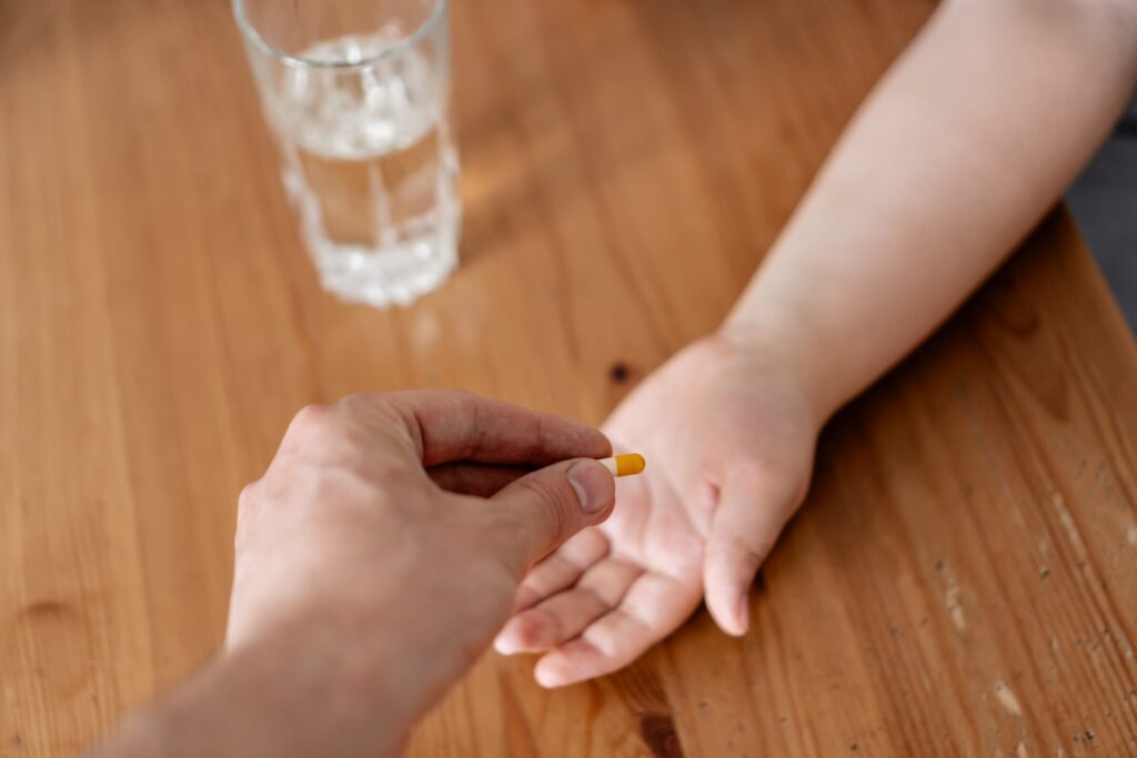 parent,giving,prescribed,pill,to,his,sick,shild,at,home.
