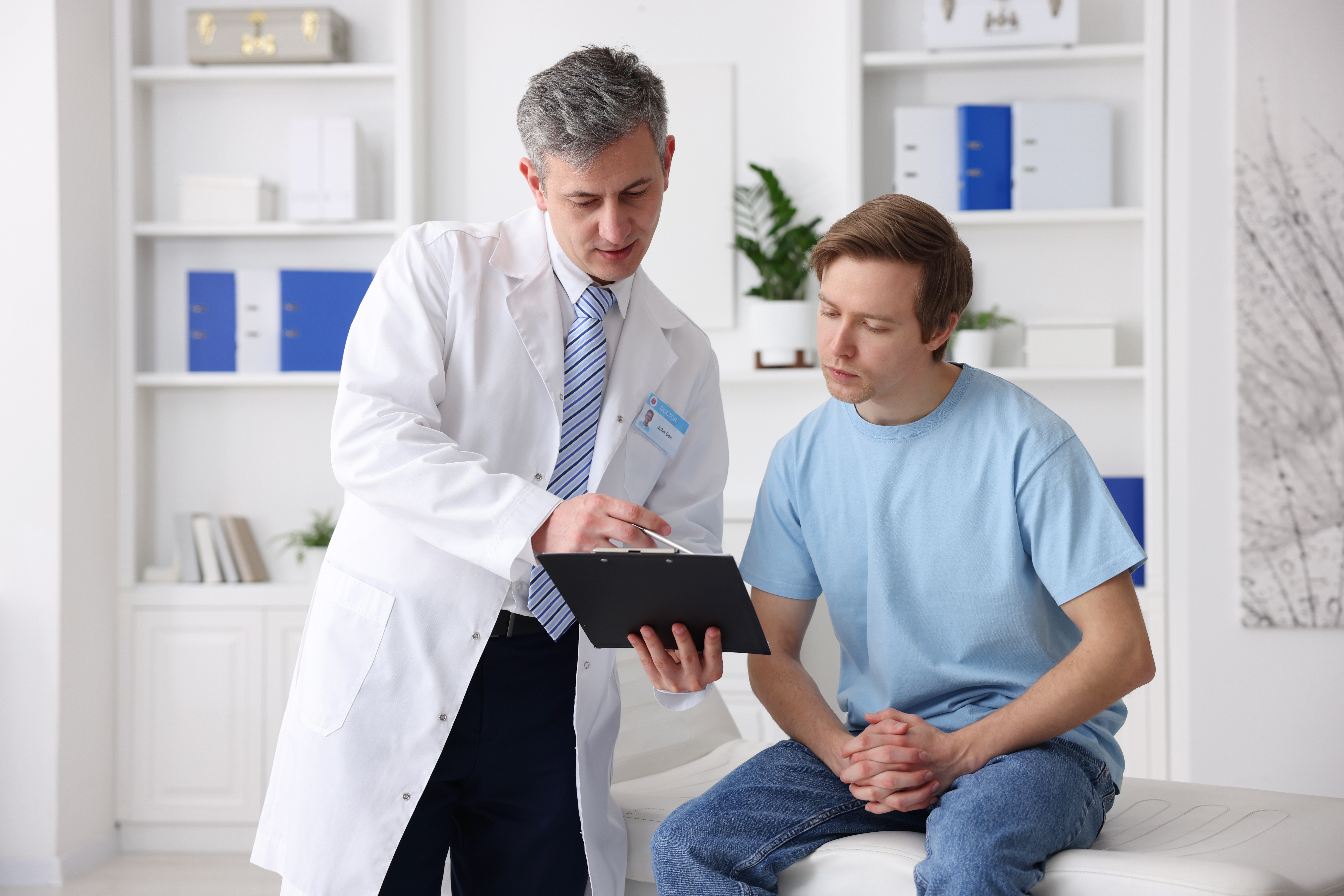 urologist,showing,clipboard,to,patient,in,clinic