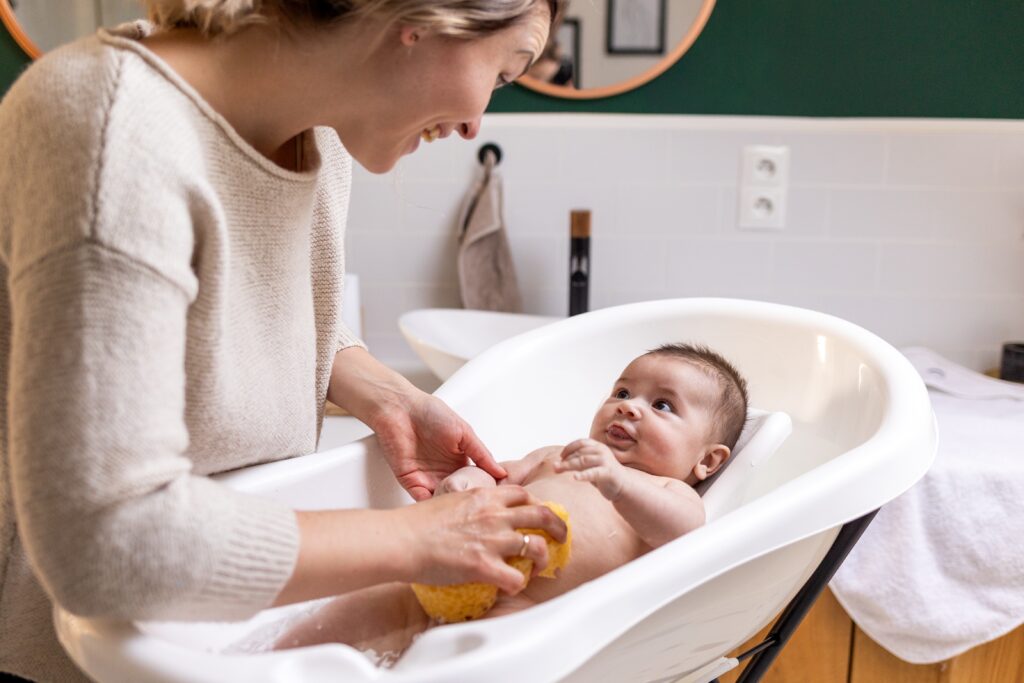 mother,washing,her,smiling,baby,in,bathtub