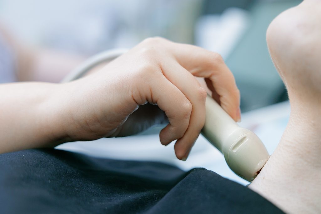 closeup,neck,ultrasound,examination,with,handheld,probe,for,diagnostic,imaging.