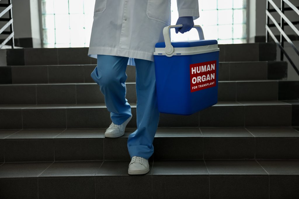 doctor,holding,cool,box,for,human,organ,on,stairs,in