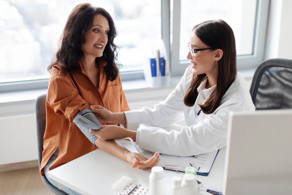 woman,doctor,wearing,armband,for,measuring,blood,pressure,with,digital