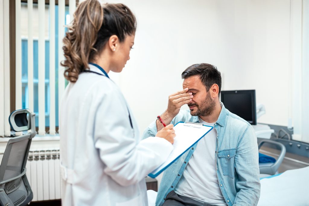 male,patient,with,headache,talking,to,doctor,in,clinic.,professional